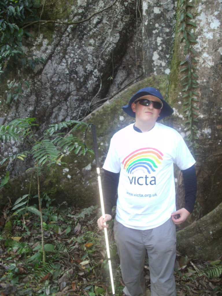 Charlie wearing his VICTA t shirt in front of a waterfall