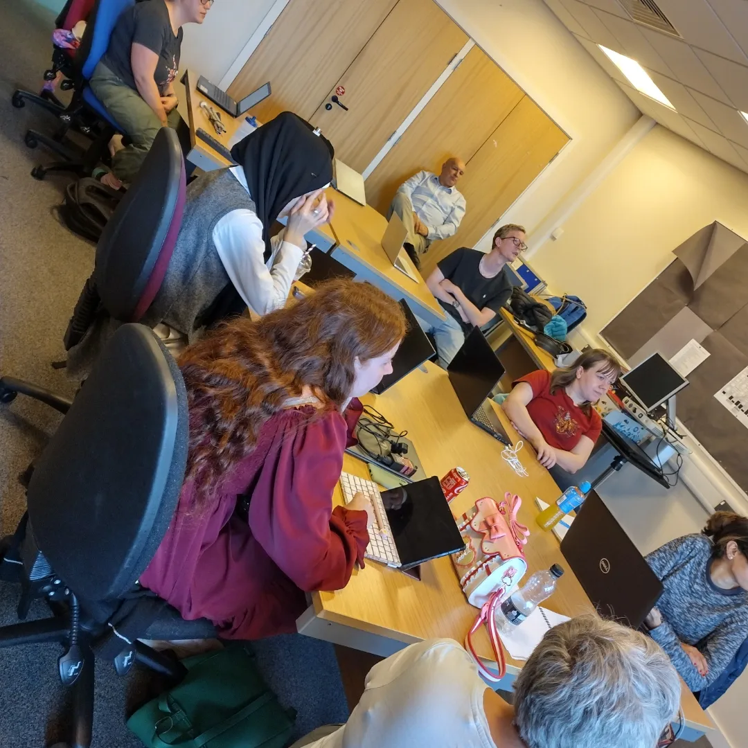 Group of young adults sitting around tables with their laptops open during one of the sessions