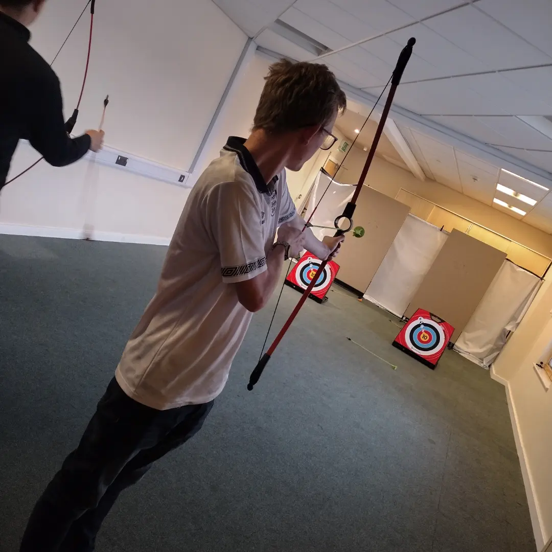 A young male is trying indoor archery