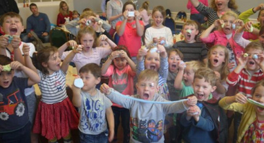 children at a Devon Science day cheering and holding up slime