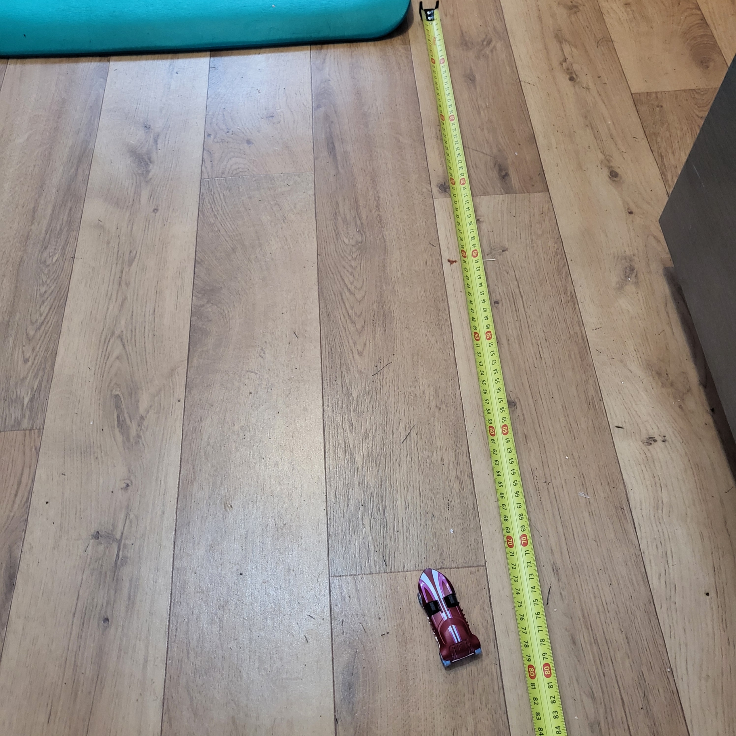 Measuring how far the car travelled on the wooden floor