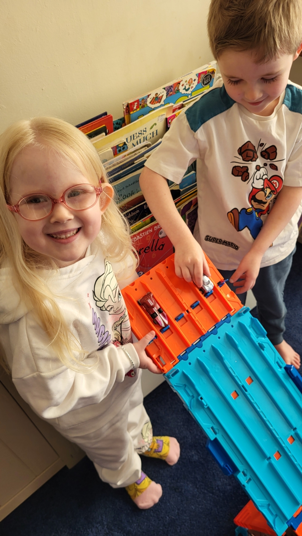 Tallulah and her brother are holding a multi-lane Hot Wheels track on a steep slope ready to race the cars down it.