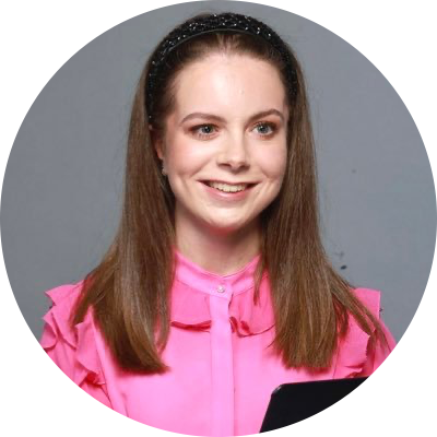 Photo of Charlotte smiling at the camera. She is wearing a frilled pink blouse.