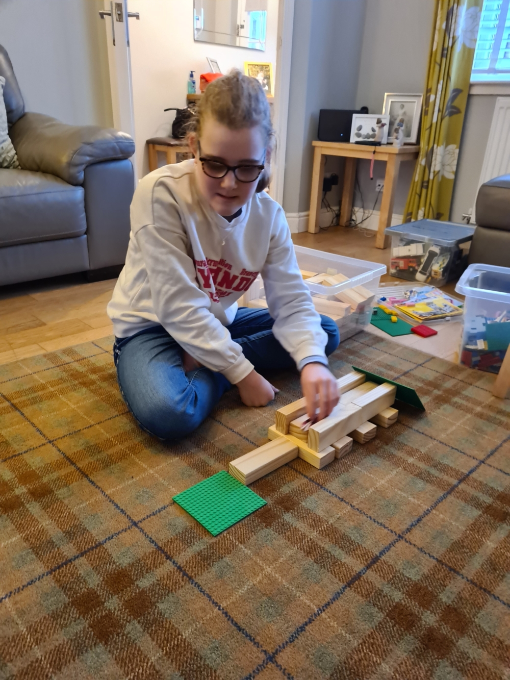 Felicity has made a track from Jenga blocks and is pushing the car through it.