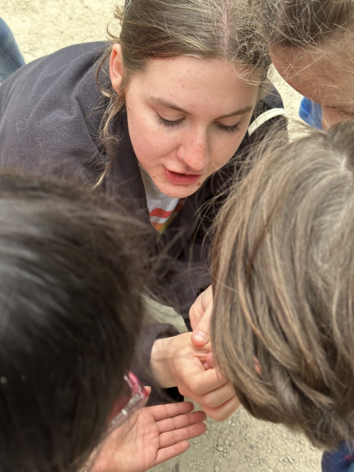 A VICTA volunteer carefully shows children a mini beast