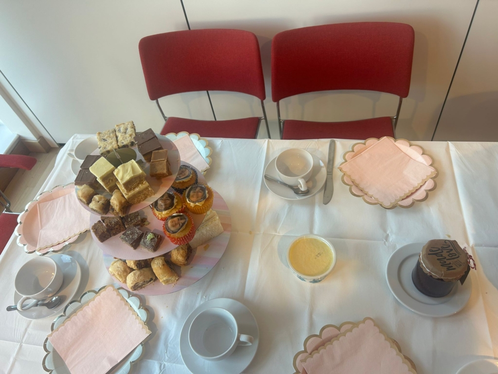 Birds eye view of cakes on a stand and china tea cups.