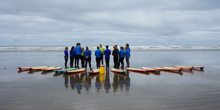 Surfers listening to the instructor on the beach